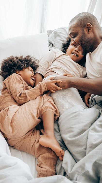 happy father playing with children on bed